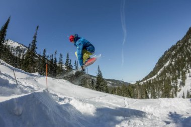 Snowboard freerider orman ve dağlar bir arka plan üzerinde bir kar rampa güneşin üzerinden atlama