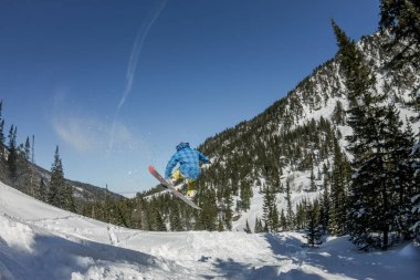 Snowboard freerider orman ve dağlar bir arka plan üzerinde bir kar rampa güneşin üzerinden atlama