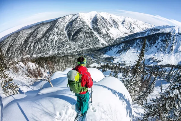 Un hombre parado en la cima de la cresta. Esquí de montaña. Aventura invierno freeride deporte extremo — Foto de Stock