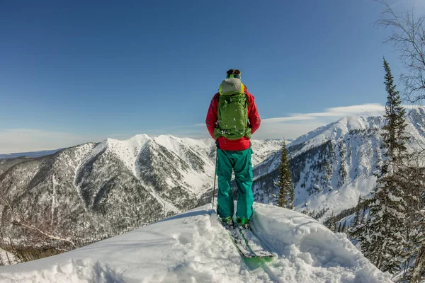 Un hombre parado en la cima de la cresta. Esquí de montaña. Aventura invierno freeride deporte extremo — Foto de Stock