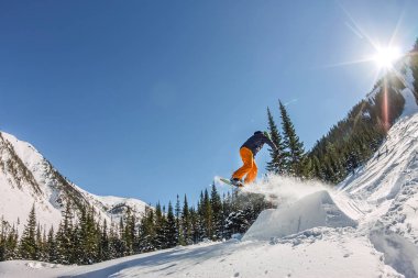 Snowboard freerider orman ve dağlar bir arka plan üzerinde bir kar rampa güneşin üzerinden atlama