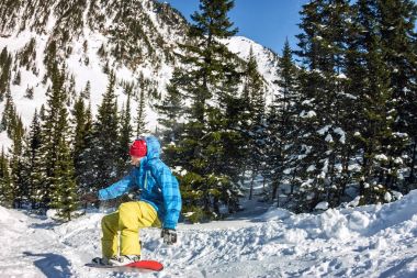 Snowboard freerider orman ve dağlar bir arka plan üzerinde bir kar rampa güneşin üzerinden atlama