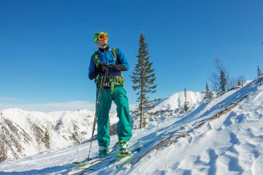 Man skier freerider standing at top of ridge, adventure winter freeride extreme sport clipart