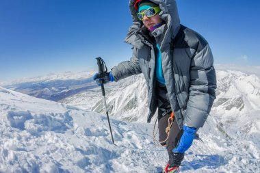 kadın dağcı kask içinde ve ceket trekking sopa ile aşağı şafakta yokuş yukarı gider