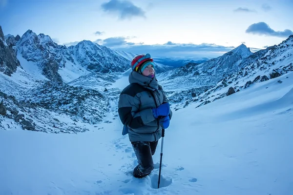 Mujer escaladora en casco y chaqueta con bastones de trekking va cuesta arriba al amanecer — Foto de Stock