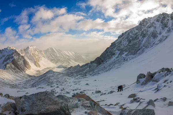 Mulher alpinista no capacete e jaqueta com paus de trekking sobe ao amanhecer — Fotografia de Stock