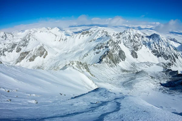 Alpinistas amarrados escalando montanha com campo de neve amarrado com uma corda com machados de gelo e capacetes — Fotografia de Stock