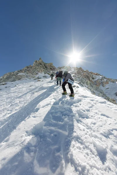Tied climbers climbing mountain with snow field tied with crampons with ice axes and helmets — Stock Photo, Image