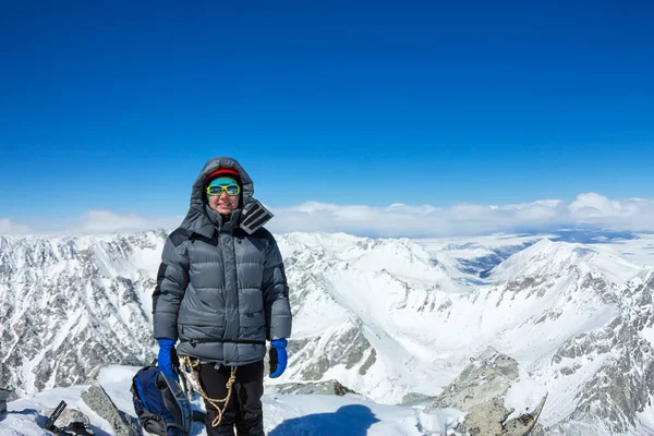 Escaladora en casco y chaqueta con bastones de trekking en la cima de una montaña — Foto de Stock