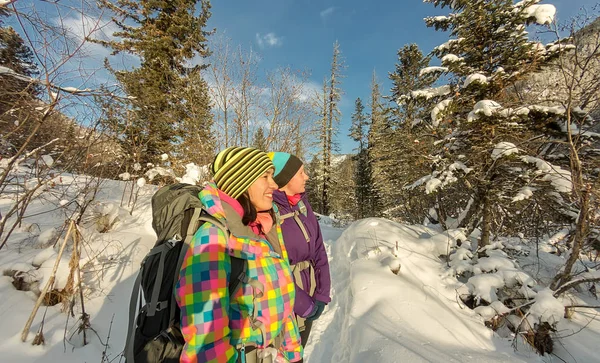 Two happy women traveler with backpacks walking in winter forest — Stock Photo, Image