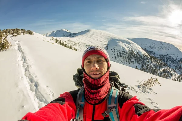 Selfi viajero masculino con una mochila en las montañas de invierno — Foto de Stock