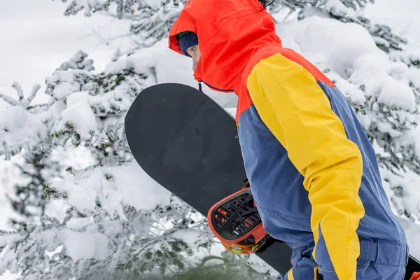 Freerider with a snowboard in overalls stands on top of a snowy mountain — Stock Photo, Image