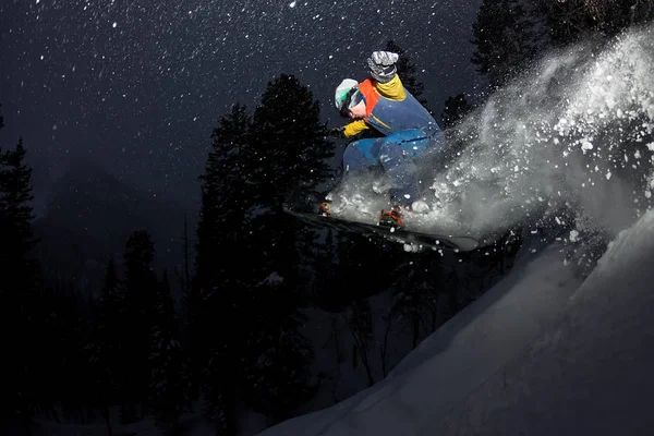 Freerider snowboarder saltando de noche con un trampolín en el bosque — Foto de Stock