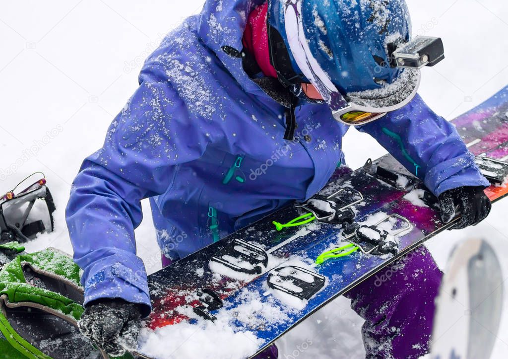 Woman freerider installs splitboard, in snow wild mountains