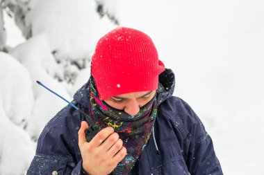 Freerider man talking on a portable radio set in a snowy forest clipart