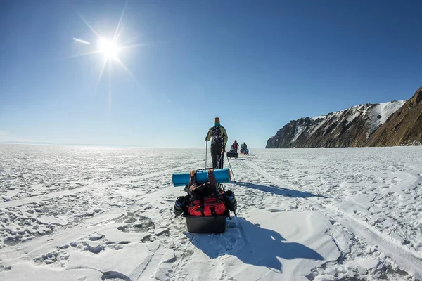Gruppo di turisti con slitte di ghiaccio a piedi lungo il ghiaccio del lago Baikal — Foto Stock