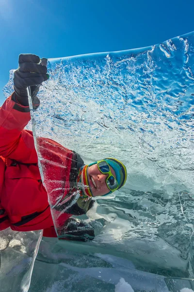 Menina olha através de um floe de gelo transparente no lago baikal — Fotografia de Stock