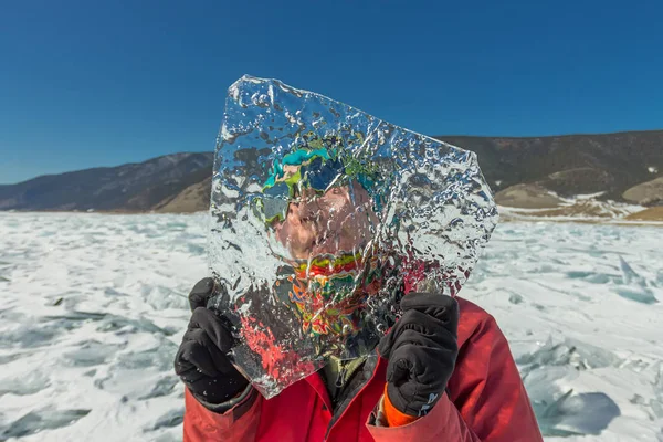 Mädchen blickt durch eine transparente Eisscholle auf den Baikalsee — Stockfoto