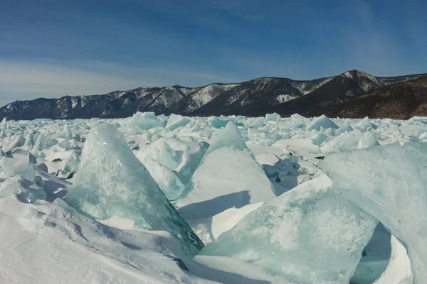 Dageraad in de blauwe hummocks van ijs het Baikalmeer, op een besneeuwde gebied in de winter op een reis — Stockfoto