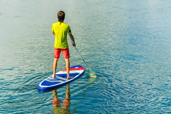 Sup surfing man stand up paddle boarder paddling at sunset on river