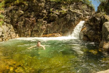 Adam bir kayalık gorge bir şelale turkuaz lagün içinde yüzüyor