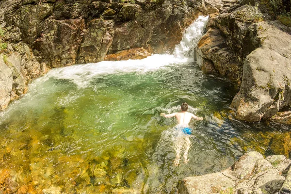 L'homme nage dans le lagon turquoise d'une cascade dans une gorge rocheuse — Photo