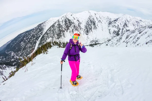 電話とスノーシューで雪の山の中でハイキングする女性。バックパック — ストック写真