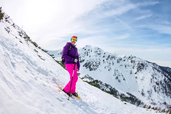 Mujer caminando en las montañas nevadas con un teléfono y raquetas de nieve. y mochila — Foto de Stock