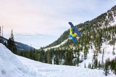 Snowboard freerider orman ve dağlar bir arka plan üzerinde bir kar rampa güneşin üzerinden atlama