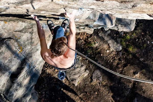 Male climber with a naked torso climbs onto a rock with top insurance — Stock Photo, Image