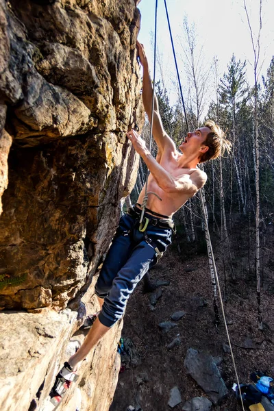 Male climber with a naked torso climbs onto a rock with top insurance — Stock Photo, Image