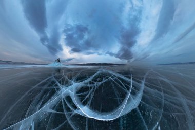 Baykal Gölü 'nün buzu, gün batımında Elenka adası yakınlarında gri bulutların altında çatırdıyor. Geniş görünüm