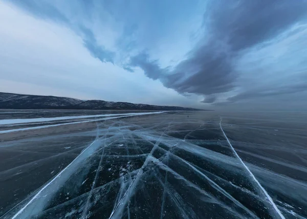 Ghiaccio del lago Baikal in crepe vicino all'isola di Elenka al tramonto sotto nuvole grigie. Ampio panorama — Foto Stock