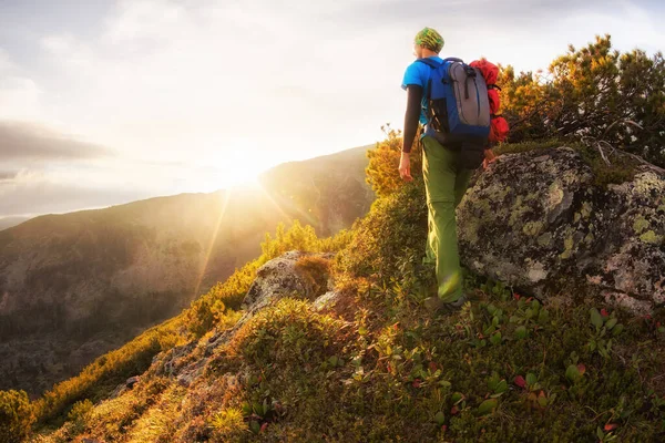 Escursionista con zaino a piedi lungo un sentiero di montagna sullo sfondo dell'alba Foto Stock