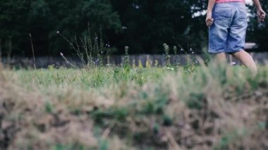 Kız çimlerde yürüyor. Kadın ayakları yeşil çimenlerin üzerinde yürüyüş