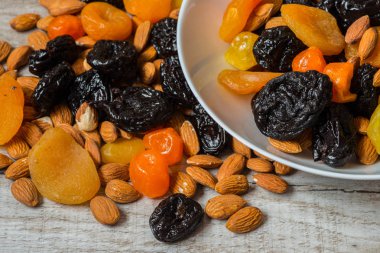 Kuru erik, Kuru Kayısı, Kuru mandalina ve badem hafif ahşap arka plan üzerinde bir kasede