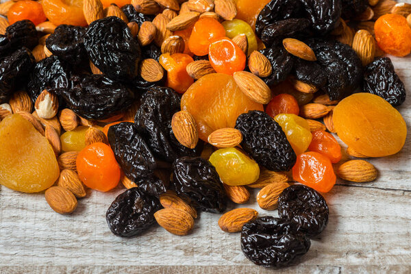 prunes, dried apricots, dried mandarins and almonds on a light wooden background