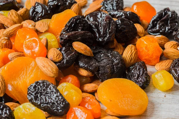 Prunes, dried apricots, dried mandarins and almonds on a light wooden background — Stock Photo, Image