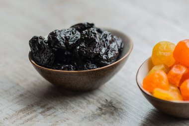 ahşap arka plan üzerinde kurutulmuş meyveler ile iki tabak: kurumuş mandalina ve kuru erik