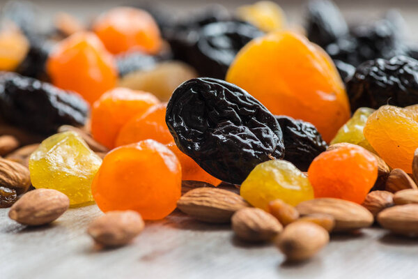 prunes, dried apricots, dried mandarins and almonds on a light wooden background