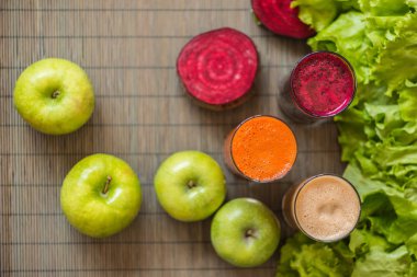 farklı taze meyve suyu üç bardak. Pancar, havuç ve elma suyu gri ahşap zemin üzerine