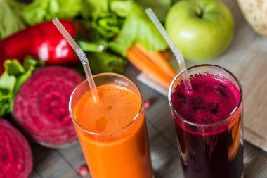 farklı taze meyve suyu iki kadeh. Pancar ve havuç suyu gri ahşap zemin üzerine