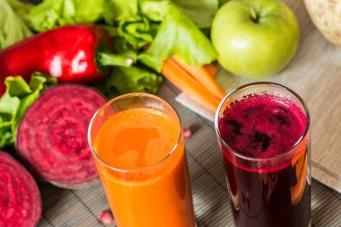 farklı taze meyve suyu iki kadeh. Pancar ve havuç suyu gri ahşap zemin üzerine