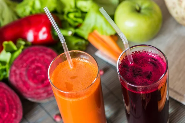 To glas af forskellig frisk juice. Rødbeder og gulerodssaft på grå træ baggrund - Stock-foto