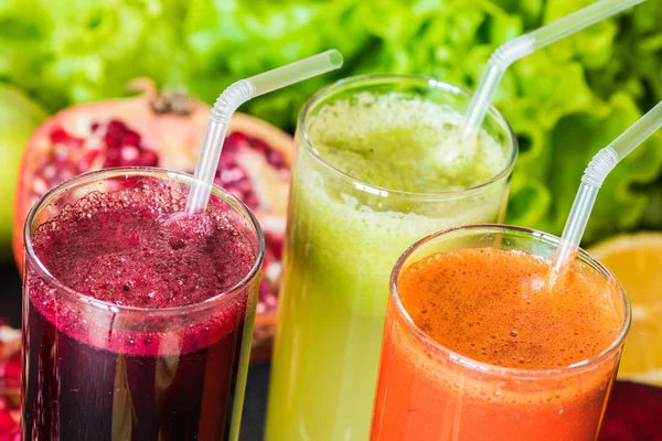 Tres vasos de jugo fresco diferente. Zumos de remolacha, zanahoria y kiwi sobre fondo gris — Foto de Stock