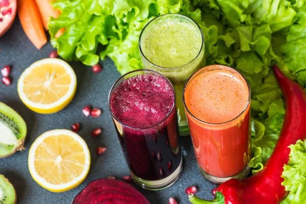 Tres vasos de jugo fresco diferente. Zumos de remolacha, zanahoria y kiwi sobre fondo gris — Foto de Stock