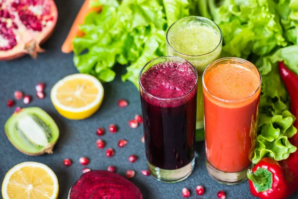 Three glasses of different fresh juice. Beet, carrot and kiwi juices on grey background — Stock Photo, Image