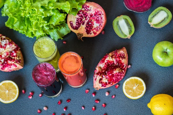 Tres vasos de jugo fresco diferente. Zumos de remolacha, zanahoria y kiwi sobre fondo gris — Foto de Stock