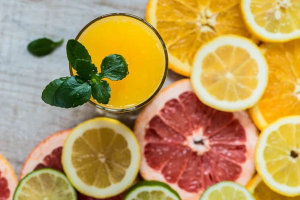 Glas apelsinjuice på trä bakgrund med skivor av citrus — Stockfoto