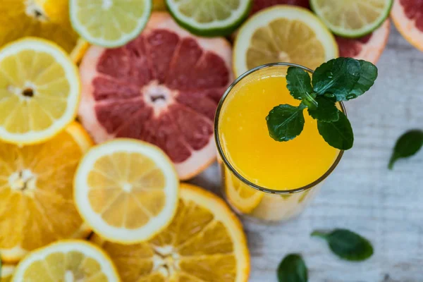 Glas apelsinjuice på trä bakgrund med skivor av citrus — Stockfoto